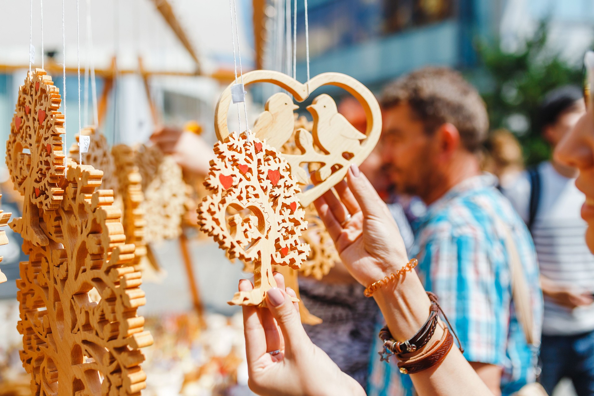 A woman tourist at a souvenir fair choosing handmade decorative woodcarving gifts